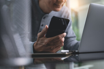 Casual man working on laptop computer using mobile phone at home office