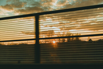 Sunset sky with clouds seen through fence lines in spring