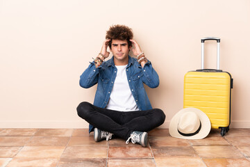 Traveler man his suitcase sitting on the floor unhappy and frustrated with something. Negative facial expression