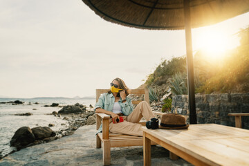 Cool beautiful girl woman traveler by the sea with a mask on her face, stylish outfit, summer travel 2020 concept