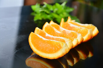 Green parsley and  orange in slices on a black glass