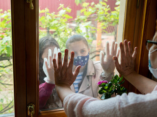 An elderly woman runs her hand through the window from the inside of her house, touching the arms...