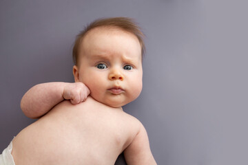 Newborn baby with blue eys isolated over gray background. Skin care, baby massage. copy space.