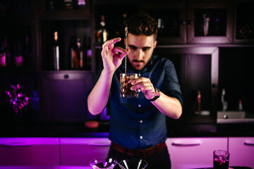 Portrait of bartender preparing fresh cuba libre with brown rum, cola, mint and lime at bar counter