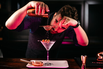 Professional bartender preparing martini with olives at bar counter.  Dry vodka martini, cocktail...