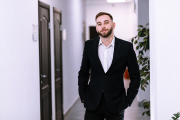 Fototapeta premium young businessman standing indoors in an office corridor