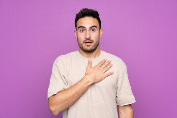 Fototapeta premium Young handsome man over isolated purple background surprised and shocked while looking right