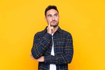 Fototapeta premium Young handsome man over isolated yellow background thinking an idea
