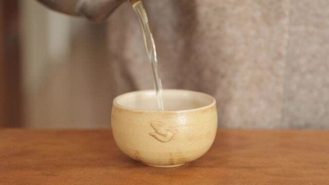Green tea : Pours into a small ceramic cup. Woman drinks it.