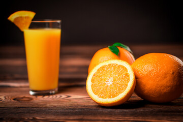 Fresh orange juice in the glass cup with oranges on old wooden table.