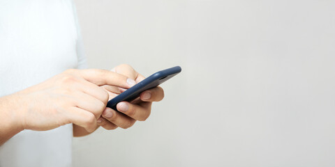 A person is holding a phone and tapping the screen on a white background with copy space. Concept of lifestyle business and Internet technologies in the office