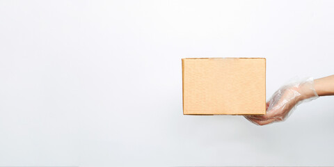 Gloved hands hold a cardboard box for online delivery of items and food on a white isolated background with copy space. Concept of the courier business of buying and ordering in a store