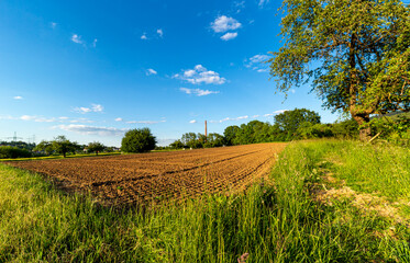 Zaorane pole na wsi. Przygotowane do siania. Produkcja jedzenia. Gospodarstwo rolne w niemczech. Komin na horyzoncie. Przemysl i rolnictwo. Pod blekitym niebem. Lato na wsi. © ff25