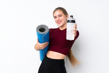 Sport teenager girl over isolated white background with sports water bottle and with a mat