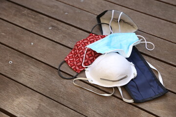 Various used medical face masks on a wooden deck. Coronavirus (covid-19) concept image. 