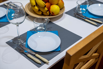 Close-up of white plate on the table with wooden chairs. Plate with fruits and wine glasses.