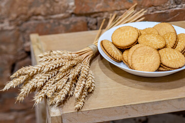 Close-up of plate with cookies on the wooden shelf. Modern loft interior. Brick wall. Decorative spikelets.