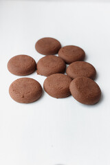 Several round brown chocolate cookies on white background top view