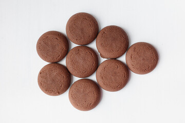 Several round brown chocolate cookies on white background top view