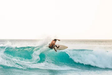 Zelfklevend Fotobehang professional surfer riding waves in Bali, Indonesia. men catching waves in ocean, isolated. Surfing action water board sport. people water sport lessons and beach swimming activity on summer vacation © William
