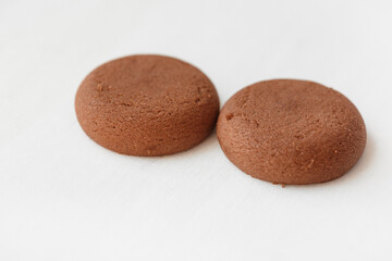Two round brown chocolate cookies on white background