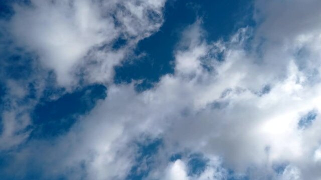 Looking up at fast moving clouds in blue sky real time