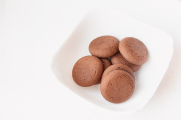 Round brown chocolate flavored cookies served in a white bowl closeup