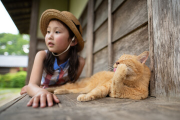 縁側でのんびり過ごす猫と少女