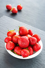 Plate with strawberries. Strawberries in a white plate on a gray background. Healthy berries.