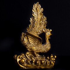 Golden chinese peacock statue ornament on a black background.