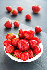 Strawberries on the table. Strawberries in a white plate on a gray background. Healthy berries.