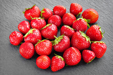 Pile of strawberries. Strawberries on a dark slate stone. Healthy berries.