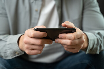Happy, young man playing game on smartphone at home