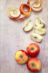 red cutted apples and peel on wooden table background. Fresh fruit backdrop with copy space for text. Ripe sliced fruit concept