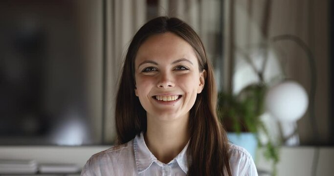 Cheerful happy young adult business woman, student or intern laughing looking at camera standing at home office. Smiling smart pretty girl with positive face expression posing for close up portrait.