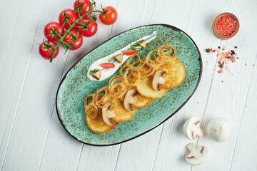 Close up view on Traditional dish of Ukrainian cuisine - potato pancakes with sour cream and mushroom on a blue ceramic plate on wooden rustic background. draniki