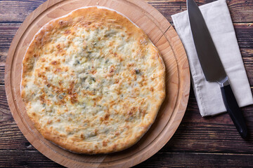 Ossetian pie with cheese and herbs (dill, parsley, scallion). Traditional Ossetian baking. Top view.