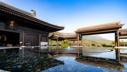 Fototapeta premium Universal Gate Hall (as written in Chinese on the wooden plague above the entrance) with a reflective pond in Tsz Shan Monastery, which is a large Buddhist temple in Tai Po, Hong Kong