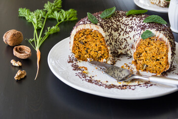 Homemade carrot cake on a large white dish on a dark wooden table. Selective focus, copy space