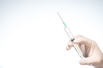 Hand wearing latex glove holding syringe with a medicine on white background