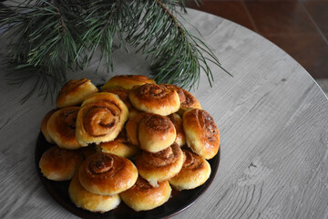 Cinnamon rolls on the table with a pine twig.