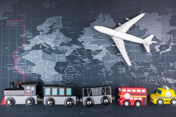 Wooden toy trains and toy airplanes on the world map. The transportation concept of the world