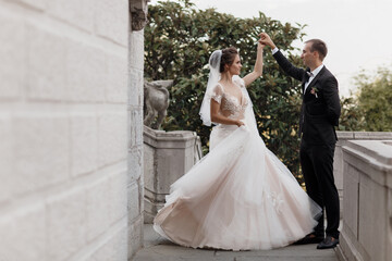 Bride and groom at wedding Day walking Outdoors on castle territory in summer.Bridal couple, Newlywed woman and man embracing with love. People happy and smile.Happy couple in love look at each other