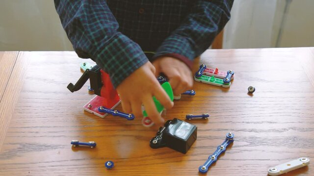 Education, children, technology, science and futuristic concept. E-learning. The boy is played by an electronic constructor. Intellectual toys. Early development concept.