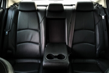 Back passenger seats in modern luxury car, frontal view, black perforated leather, Luxury car inside. Interior of prestige modern car. Comfortable leather seats. 