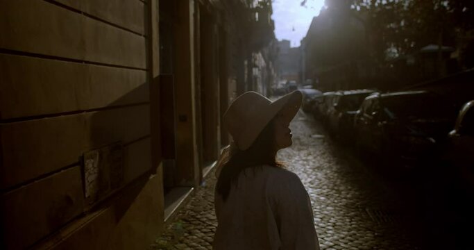 Young cute woman traveller wearing hat walks on cobblestoned street in Rome Italy enjoying the sights and getting lost discovering new city in Europe