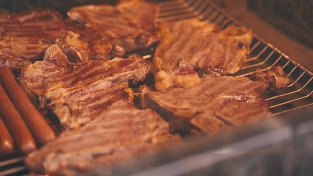 Putting sause on grilled sausages and steaks on barbecue grill