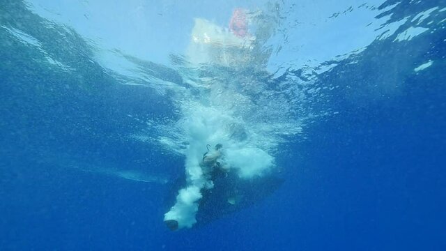 silhouette of scuba divers on surface of water underwater ascend descend sun beams and rays ocean scenery