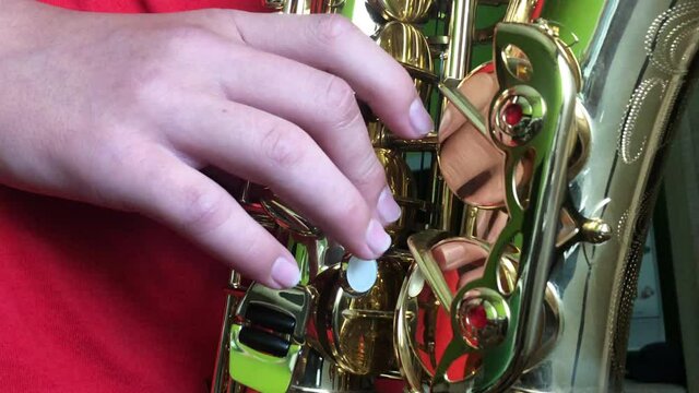 Close-up part of instrument soprano saxophone while playing music. Kid playing saxophone. Saxophonist play on golden saxophone.