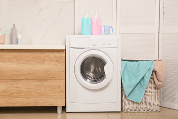 Wicker basket with laundry, detergents and washing machine in bathroom